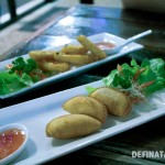 A photo of two entree dishes, calamari and vegetarian curry puffs.